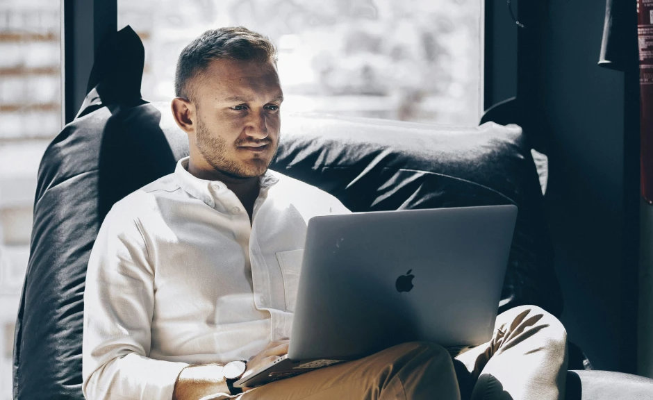 Mann sitter i sofa med PC i fanget