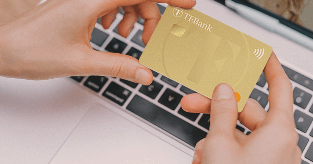 holder kredittkort i hånden foran PC