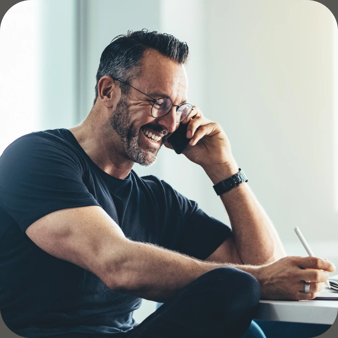 Smilende mann snakker i telefon og tar notater