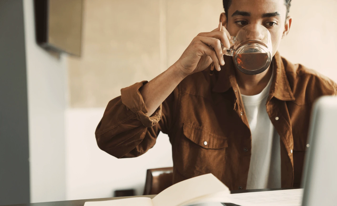 Mann drikker te og leser om hvordan man kan forstå rentefri periode med kredittkort på sin pc