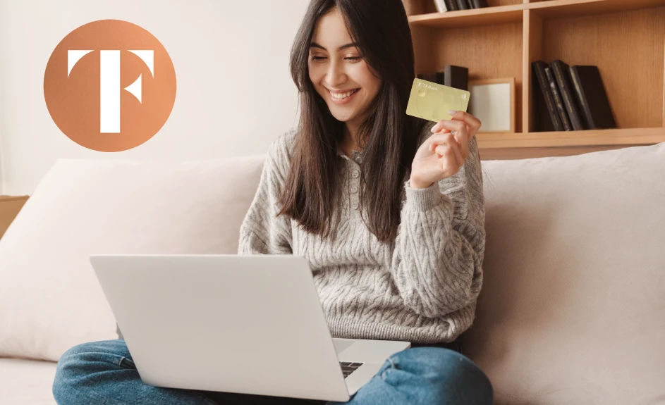smilende kvinne sitter foran pc med tf bank mastercard i hånden samt oransje tf bank logo