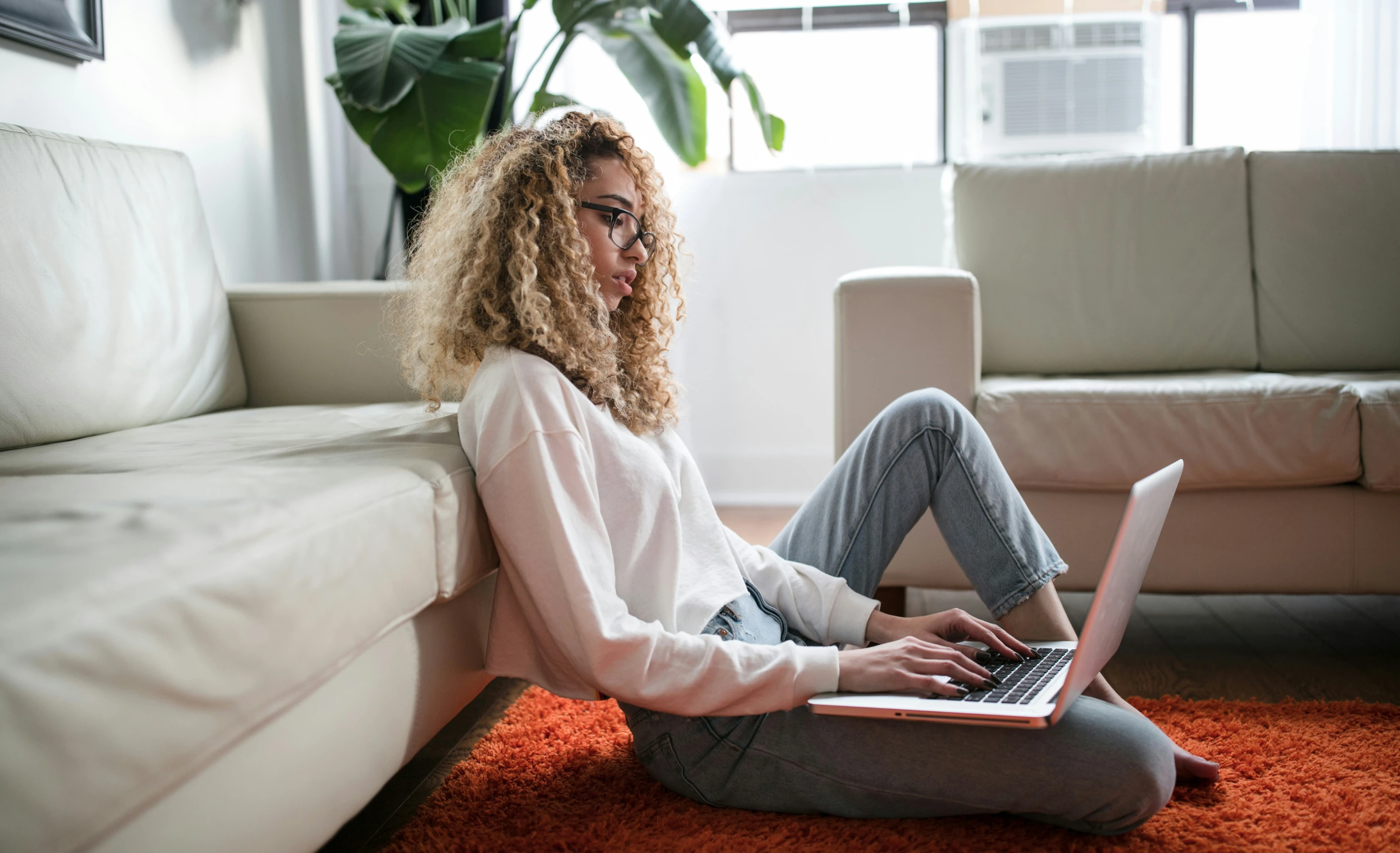 woman sitting on floor working on laptop