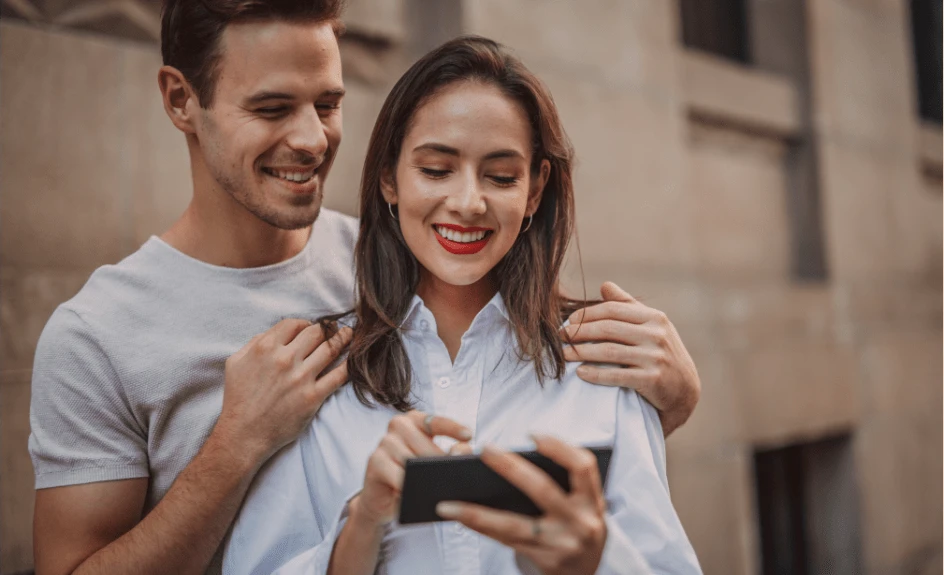 Par som ser på mobilen og vurderer kredittkort eller forbrukslån