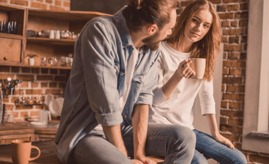 Mann og kvinne sitter på kjøkkenbenk og ser på hverandre