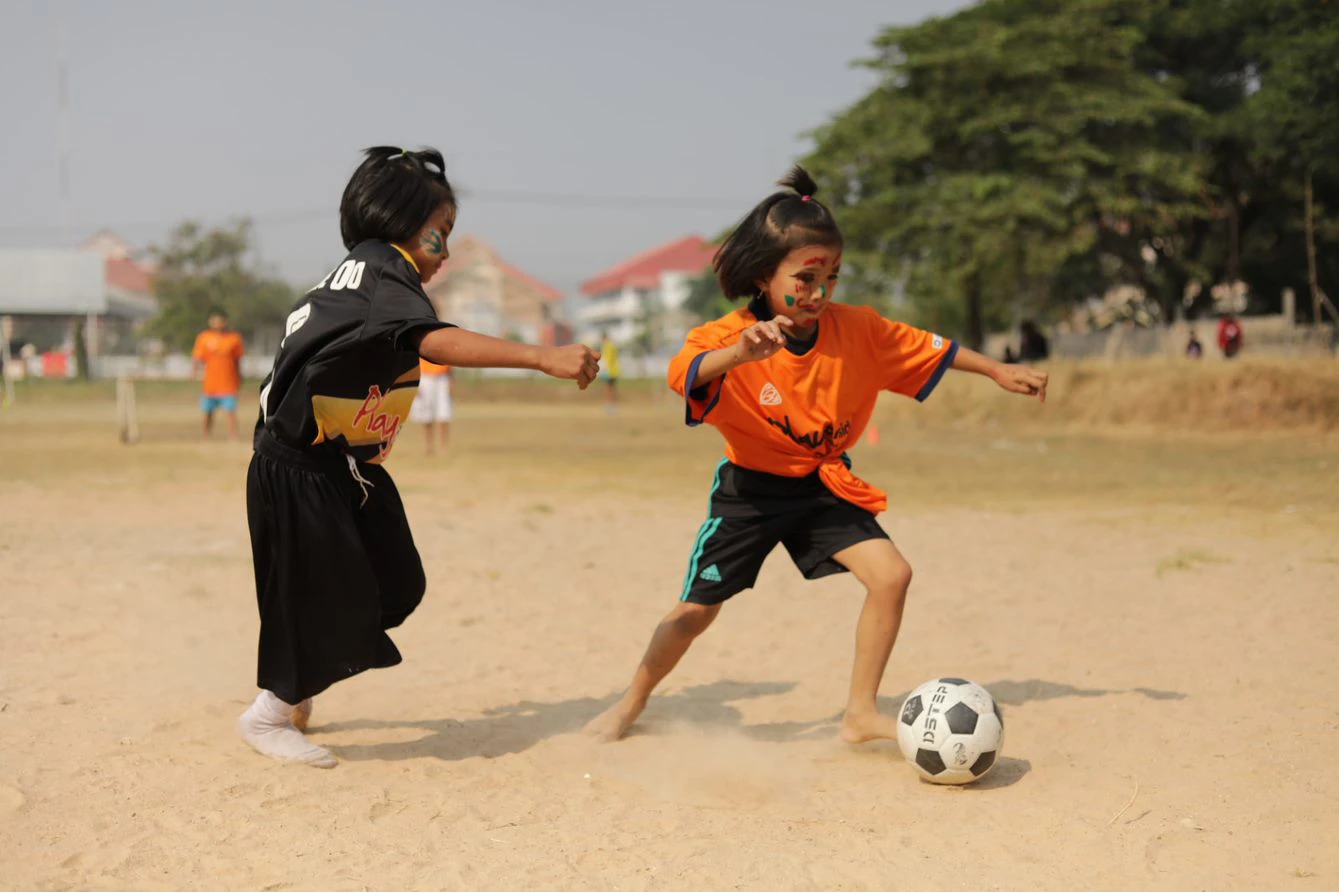 barn spiller fotball på strand