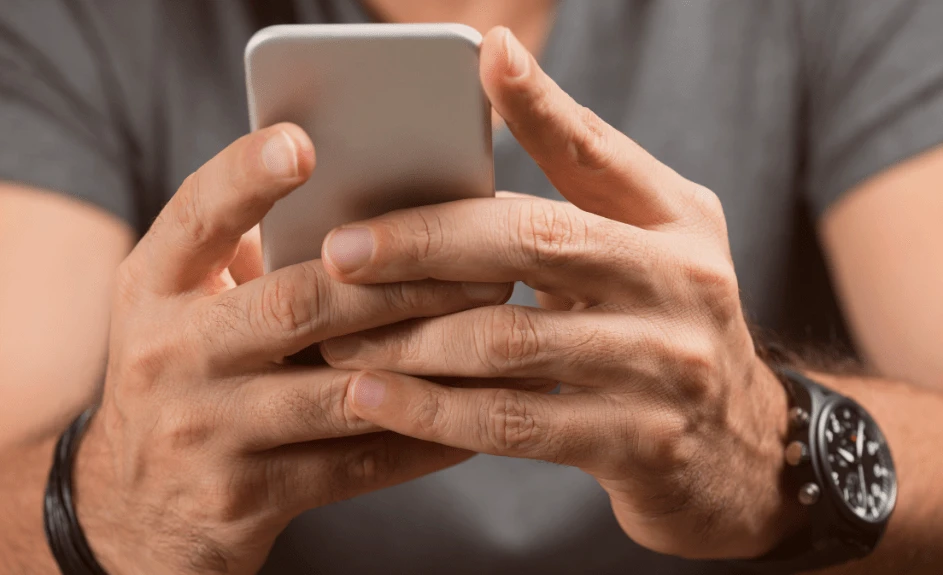 mann holder mobiltelefon i håndene