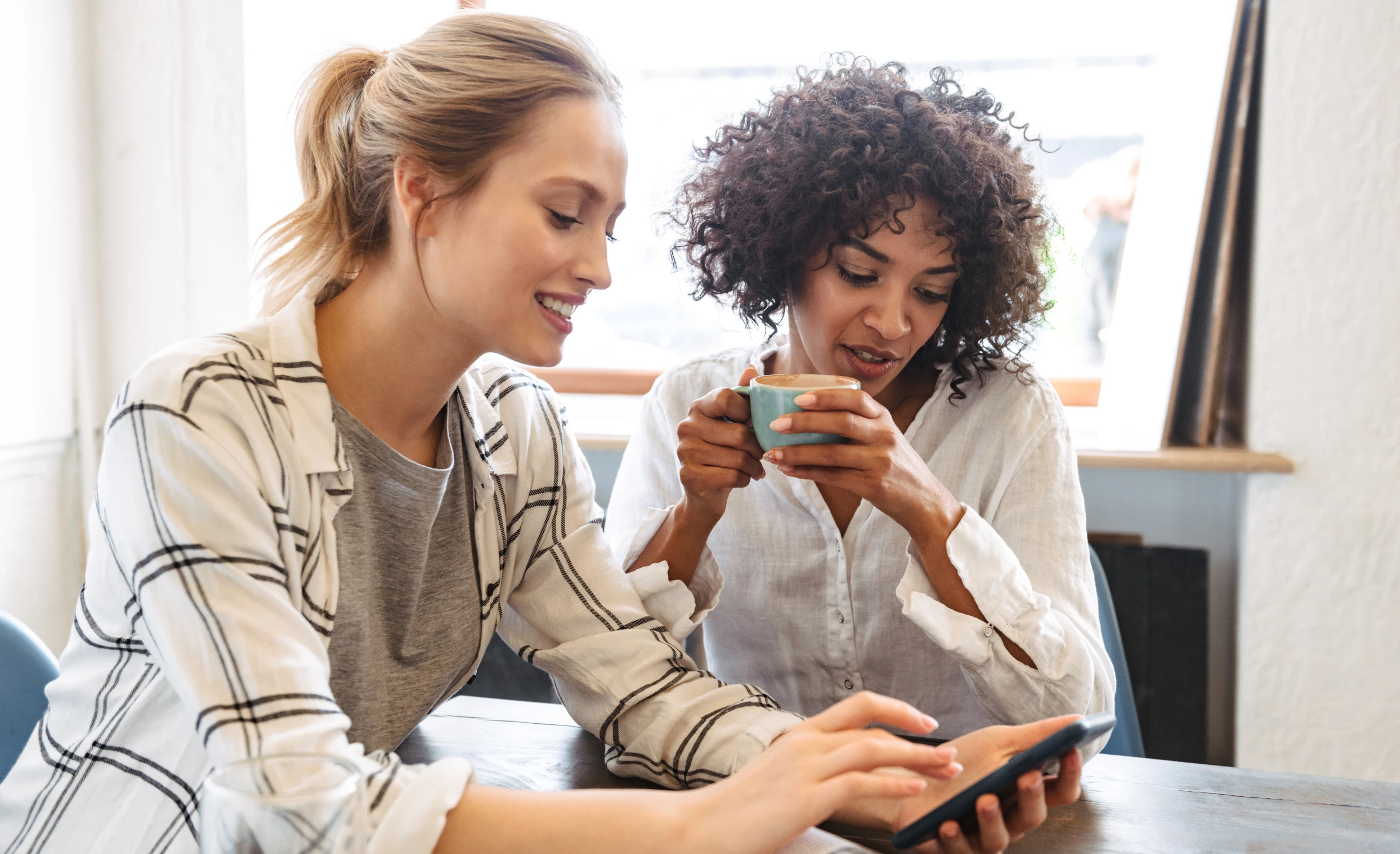 to kvinner på cafe ser på mobil