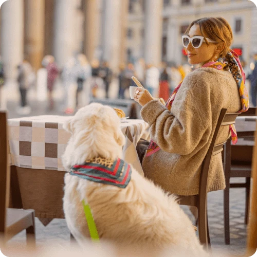 kvinne og hund sitter på uteservering