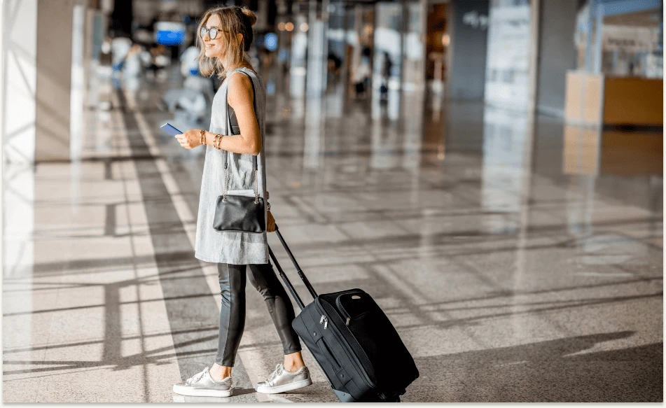 Smilende kvinne med koffert på flyplass