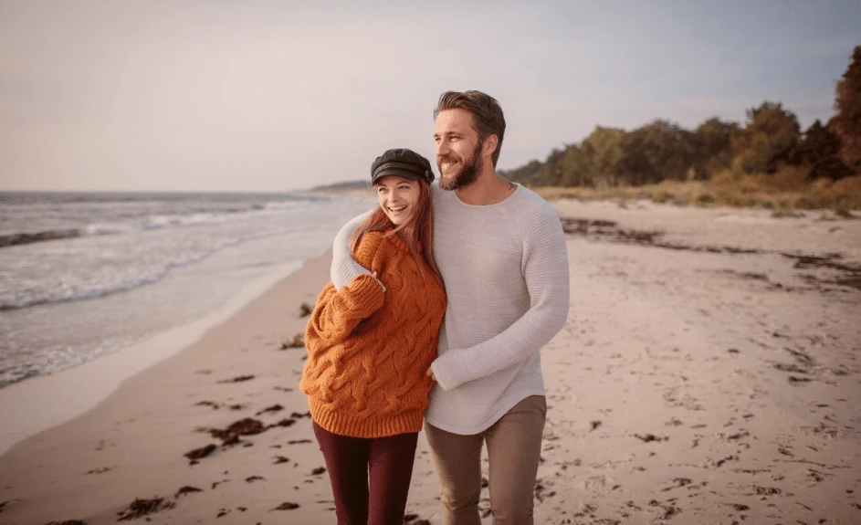 Smilende par går på strand på ferie