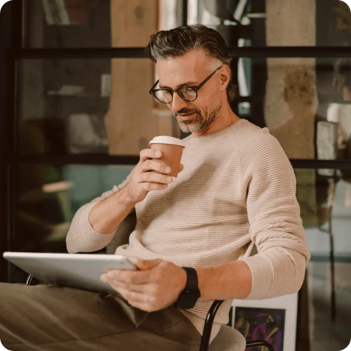 Mann drikker kaffe og ser på nettbrett