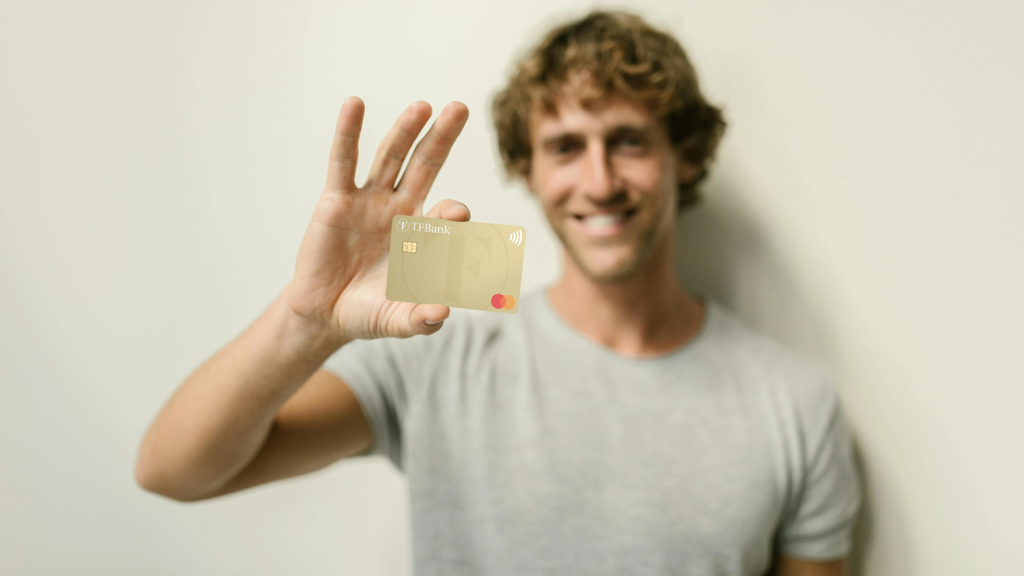 smilende mann holder tf bank mastercard opp mot kameraet