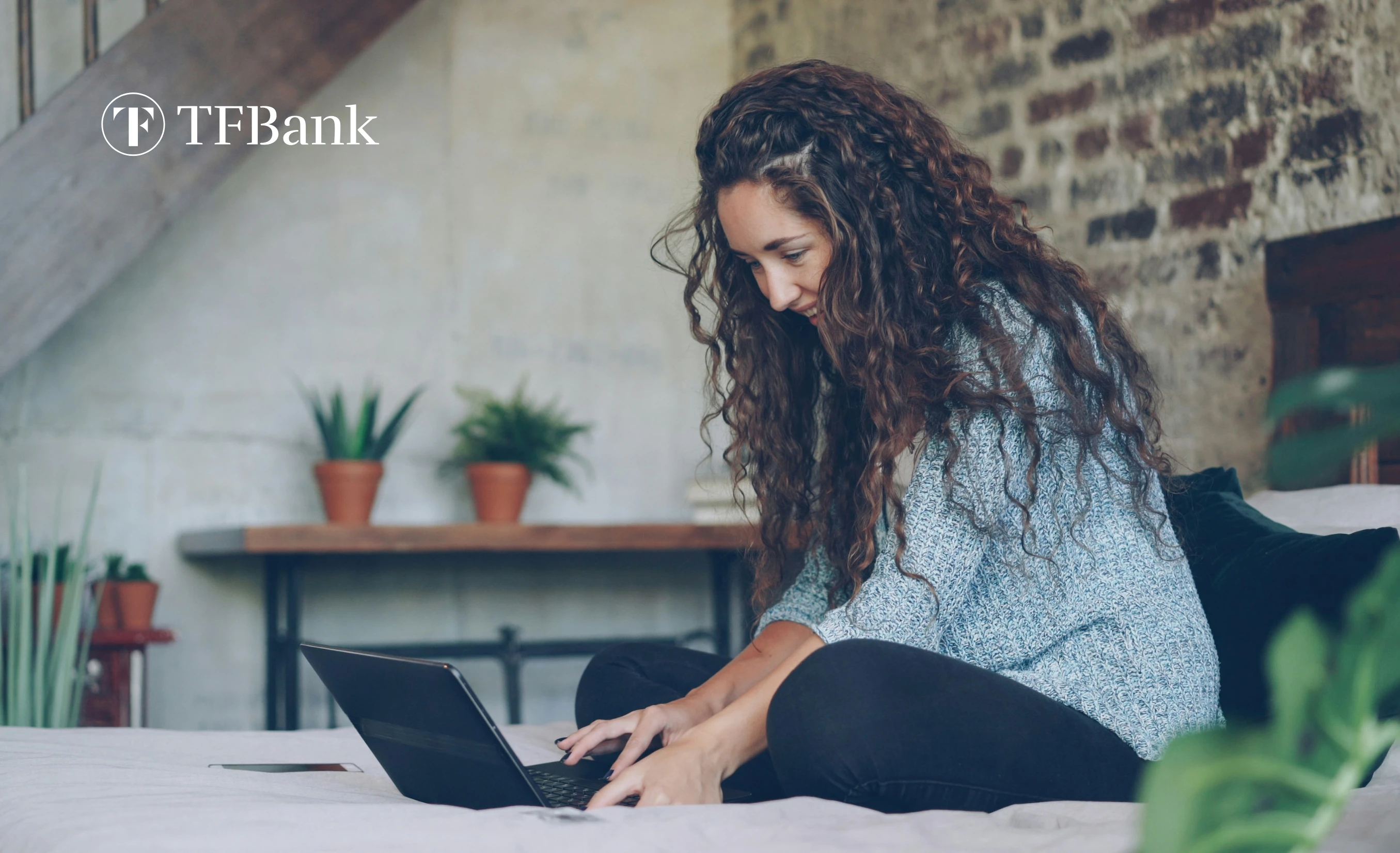 smilende jente sitter i sengen med PC