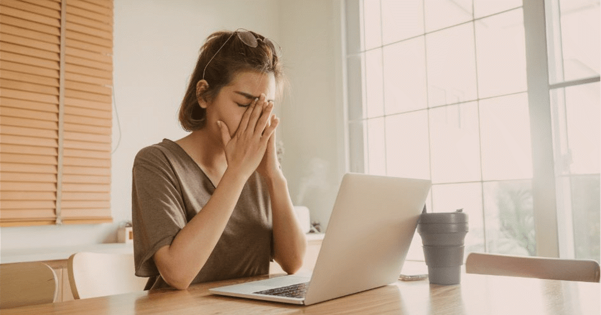 oppgitt kvinne med hendene foran ansiktet foran pc-skjerm