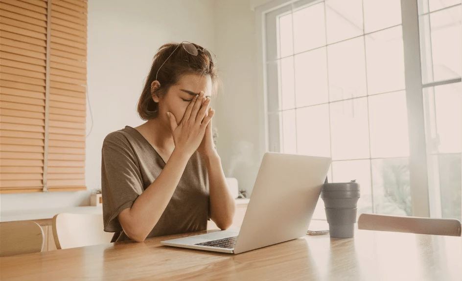 oppgitt kvinne med hendene foran ansiktet foran pc-skjerm