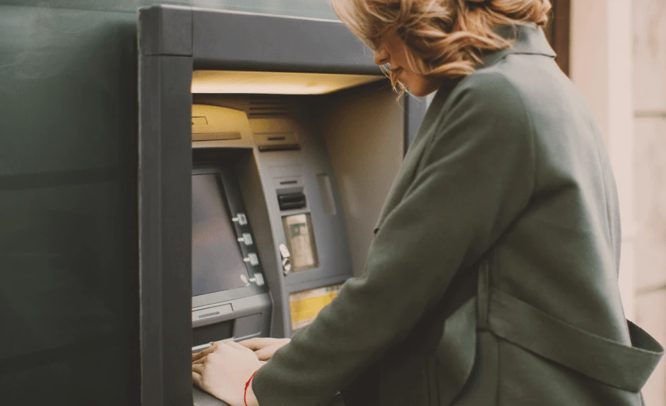 kvinne tar ut penger i minibank i utlandet med valutapåslag