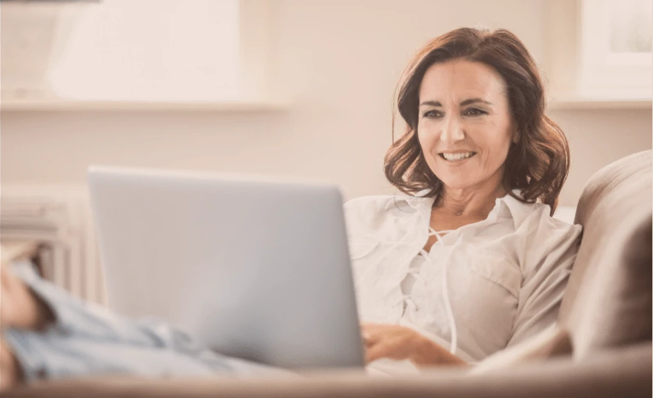 smilende kvinne sitter foran pc