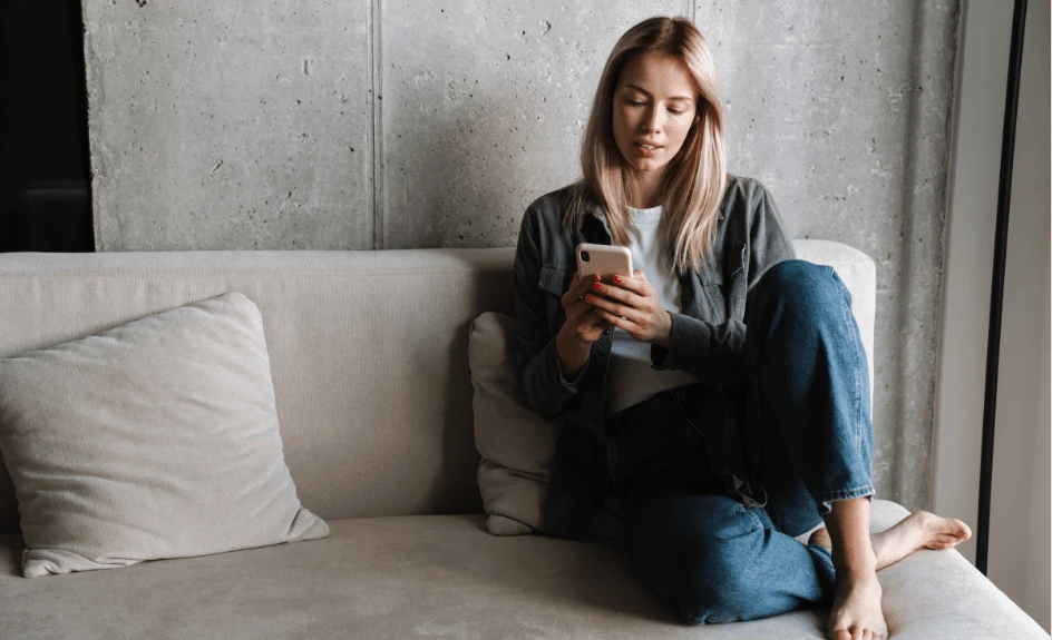 Kvinne med mobil på sofa